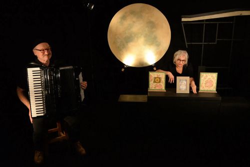 un accordeoniste et une comedienne sur scéne avec un fond noir