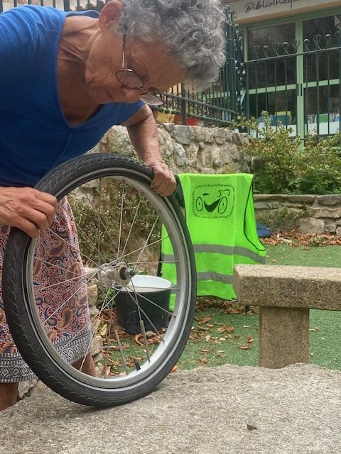 La photo représente une femme qui répare une roue de vélo